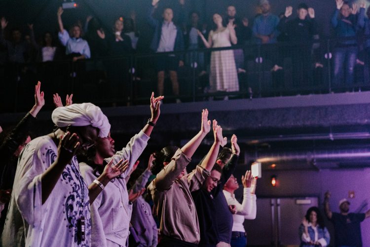 Soul City Church congregation worshipping with hands raised during a Sunday gathering